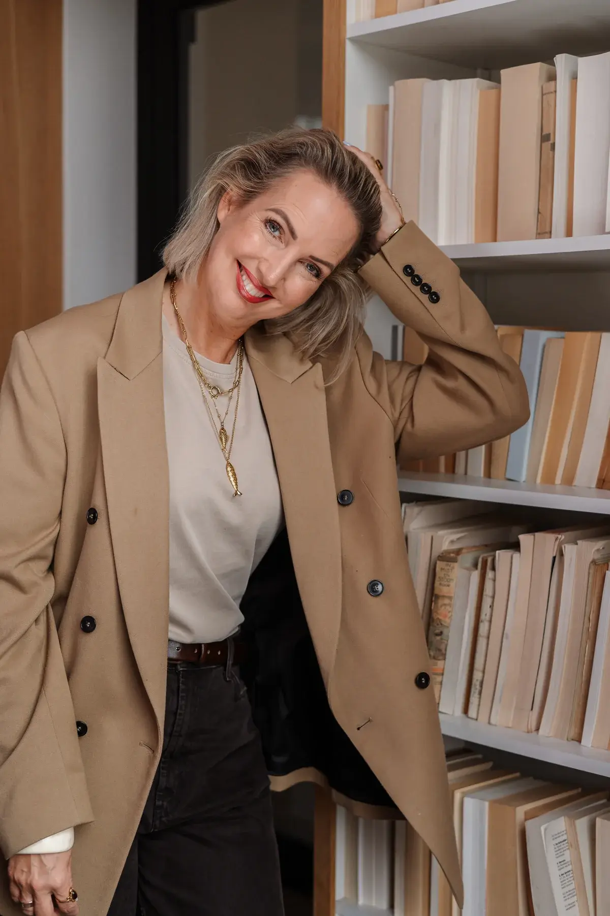 Mieke van Velzen, lachend en ontspannen bij een boekenkast